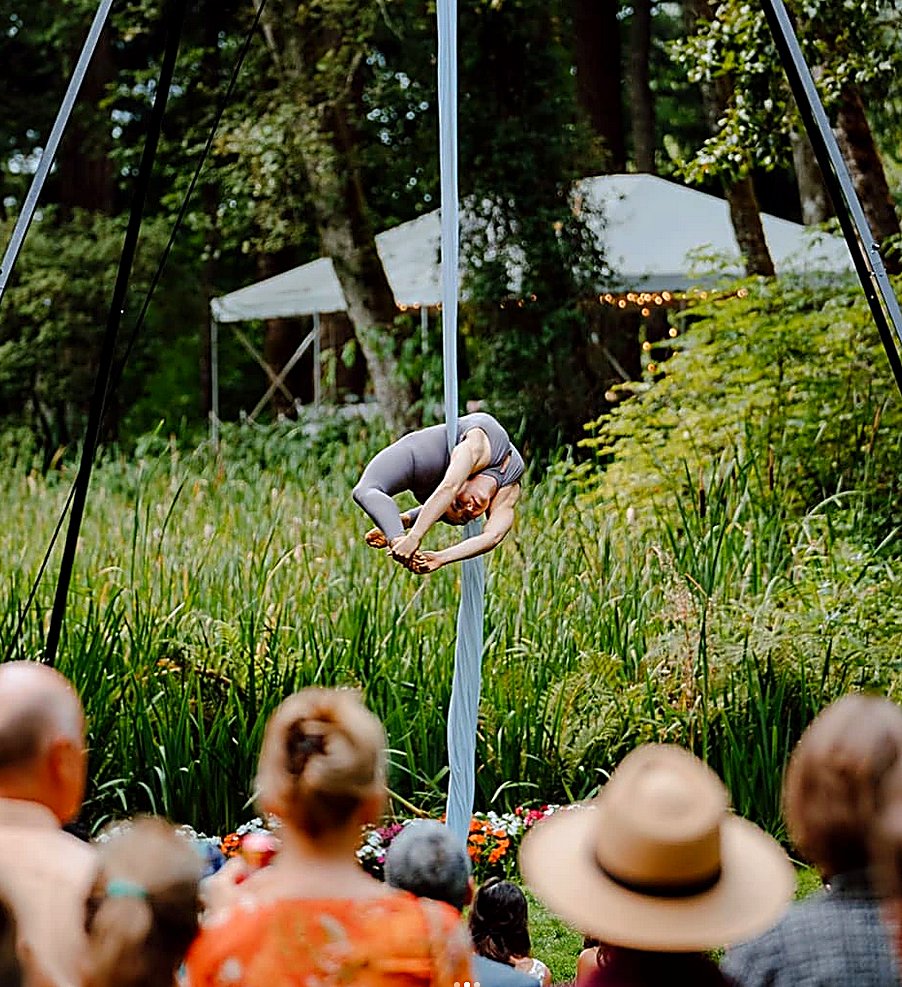 Aerial silks cocoon pose at an outdoor forest event