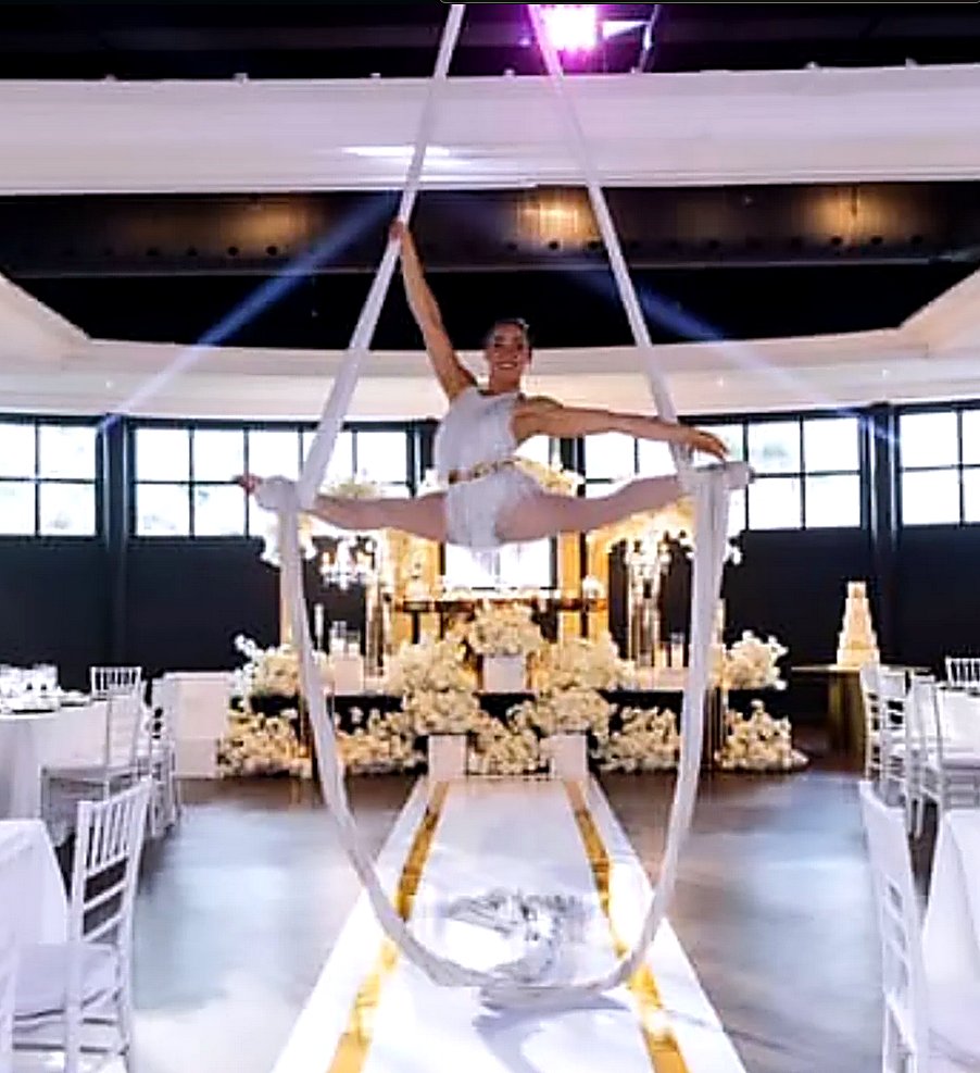 Aerial silks split pose above a wedding aisle